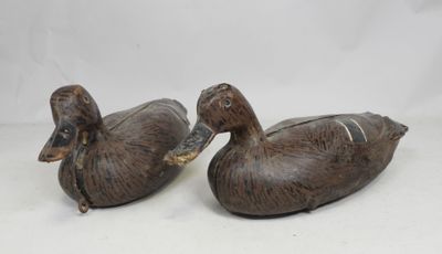 deux canards en bois posés l'un sur l'autre sur une surface blanche