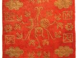 a red and gold rug with a floral design on it
