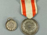 two medals and a medal on a table with a gray background