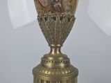 a gold vase with a picture on it on a table