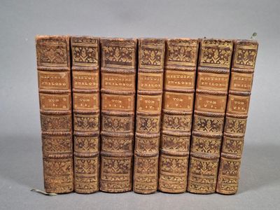 plusieurs vieux livres sont alignés sur une surface grise