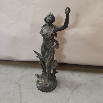 bronze statue of a woman holding a bird on a pedestal