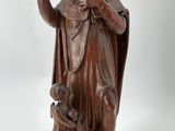 statue représentant un homme accompagné d'un chien et d'un oiseau, posée sur un socle en bois