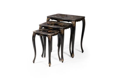 un ensemble de trois tables gigognes noires et dorées sur fond blanc