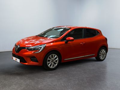 Une voiture rouge est garée dans une pièce aux murs blancs.