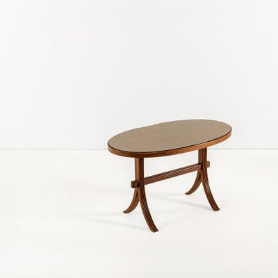 une table basse ovale avec un piètement en bois et des pieds courbés