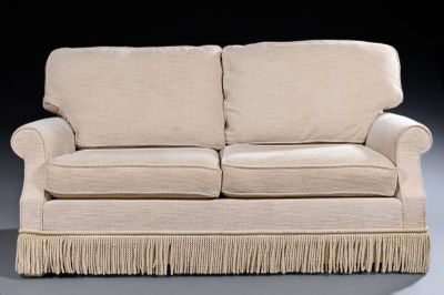 a white couch with fringes on it in a dark room
