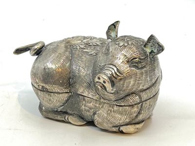 une figurine en argent représentant un cochon, posée sur un fond blanc