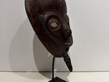 an image of a wooden mask on a stand on a white surface