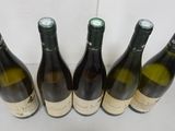 six bottles of wine are lined up on a white surface