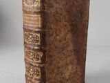 an old book sitting on top of a table next to a vase