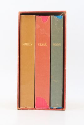 trois livres dans une boîte posée sur une surface blanche