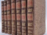 several old books are lined up in a row on a white surface