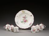 une assiette blanche ornée de fleurs roses, posée à côté d'une tasse et d'une soucoupe