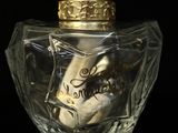 a bottle of perfume with a swan in it on a black surface