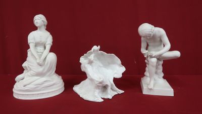 trois figurines blanches représentant une femme et un homme assis sur un rocher