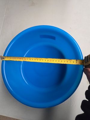 Quelqu'un mesure la hauteur d'un bol bleu à l'aide d'un mètre ruban
