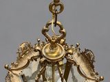an antique brass hanging light fixture with a bird on top of it