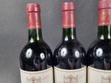 three bottles of red wine are lined up on a table