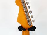 an orange electric guitar with a wooden neck and a metal bridge