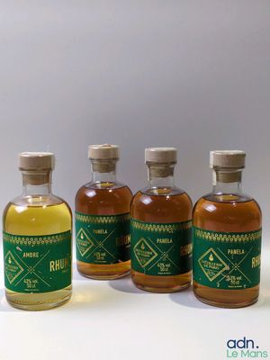 quatre petites bouteilles d'alcool sont alignées sur une surface blanche