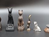 Plusieurs figurines représentant des chats et des chiens sont alignées sur une table