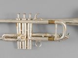 an old silver trumpet with a brass bell on a gray background