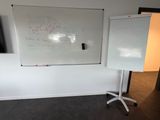 un tableau blanc accroché au mur, à côté d'une chaise blanche