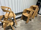 Plusieurs chaises en bois sont alignées contre un mur devant un bâtiment.