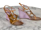 des sandales à talons compensés violettes et beiges posées sur une surface en marbre