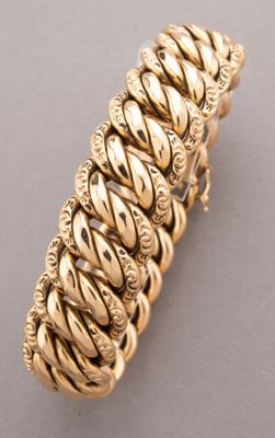 a close up of a gold bracelet on a gray surface