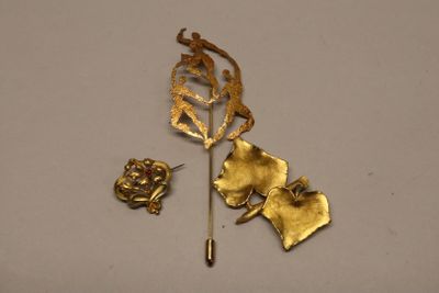 a gold brooch and a pair of earrings on a white surface