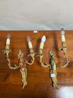 four antique wall sconces on a wooden table with a label on it