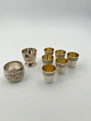 a group of silver cups and bowls on a white surface