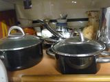 des casseroles et des poêles posées sur un plan de travail en bois dans une cuisine