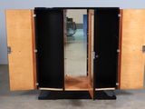 a wooden cabinet with two doors open and a mirror on top of it