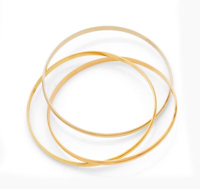 a close up of a stack of gold bangies on a white surface