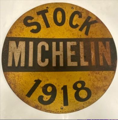 une ancienne enseigne Michel est exposée sur un fond blanc