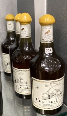 Plusieurs bouteilles de vin sont alignées sur une étagère en verre
