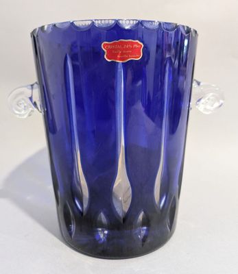 un vase en verre bleu sur lequel est collée une étiquette rouge