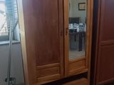 une armoire en bois surmontée d'un miroir, dans une pièce