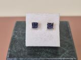une paire de boucles d'oreilles en saphir bleu posées sur un bloc de marbre