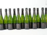 six bouteilles de champagne alignées sur une surface blanche