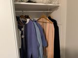 a closet with clothes and clothes hanging on the shelves