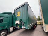 two green semi trucks parked next to each other in a parking lot