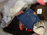 a pile of clothes in a plastic bag on a bed