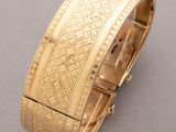 a close up of a gold bracelet on a gray surface