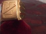 une bague en or ornée d'un « z », posée sur un coussin en velours rouge