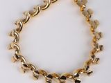 a close up of a gold bracelet on a white surface