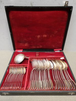 des couverts dans un étui rouge posé sur une table, avec une cuillère et un repose-cuillère